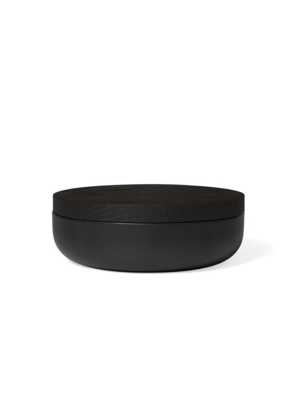 Minimalist black ceramic jars with wooden lids, part of Vincent Van Duysen's home accessories collection.