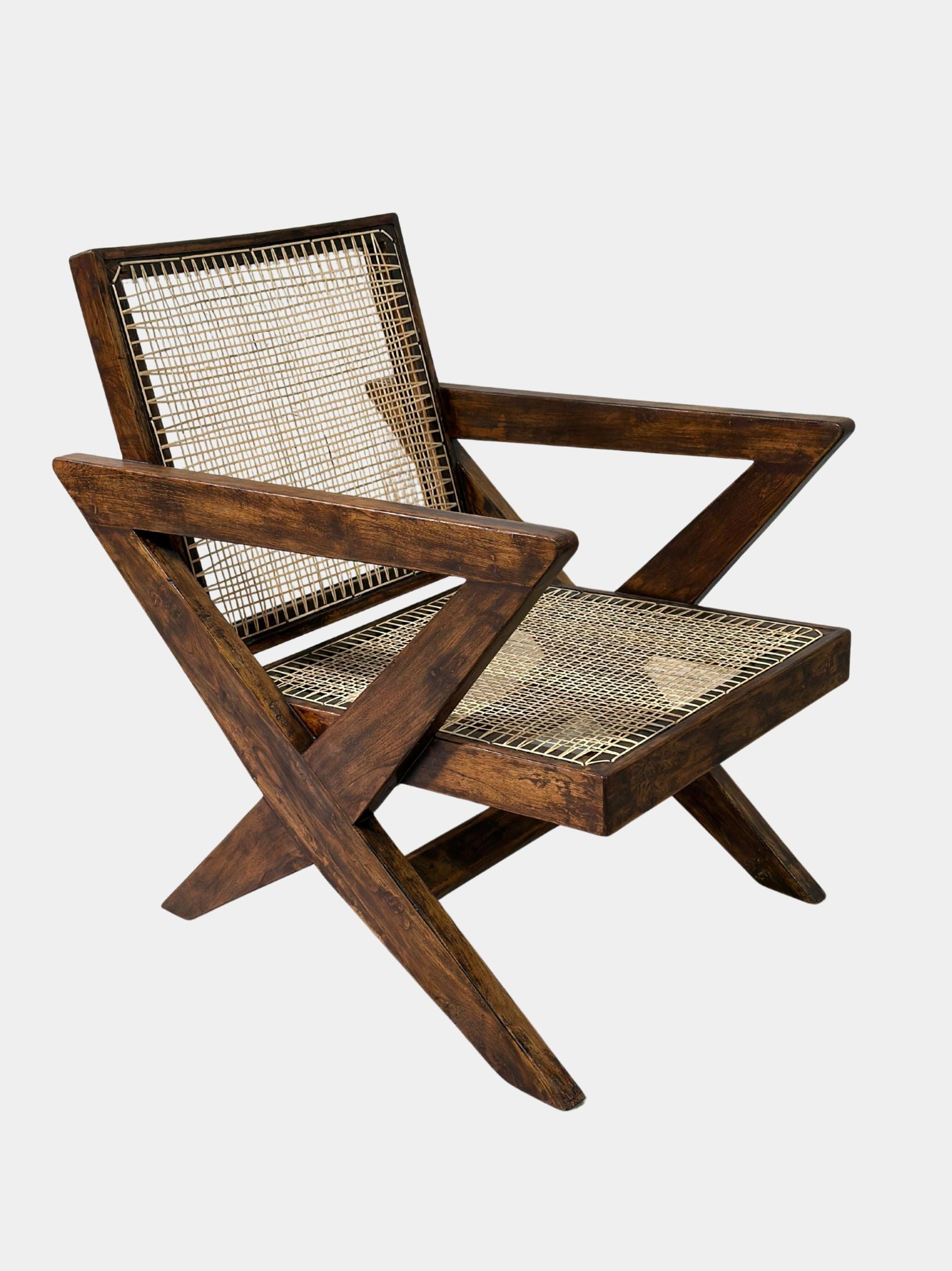 Side angle showing the angular armrest and X-leg structure of Pierre Jeanneret lounge chair, authentic Chandigarh model